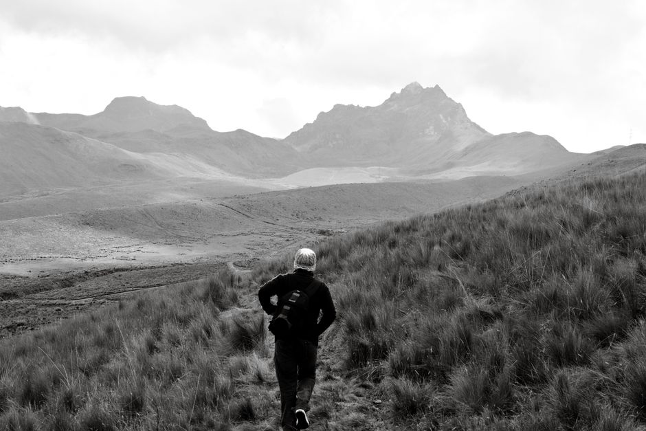 A lone hiker walks through the rugged landscapes of Ecuador's Andes Mountains.